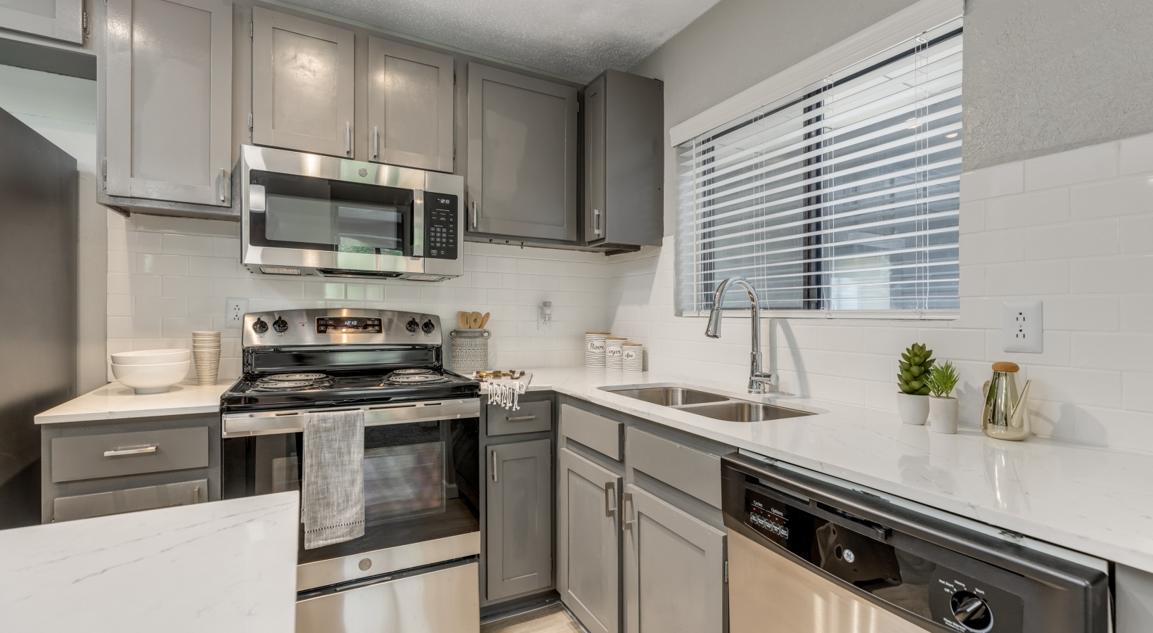 a clean kitchen with stainless steel appliances and gray cabinets at The Landon