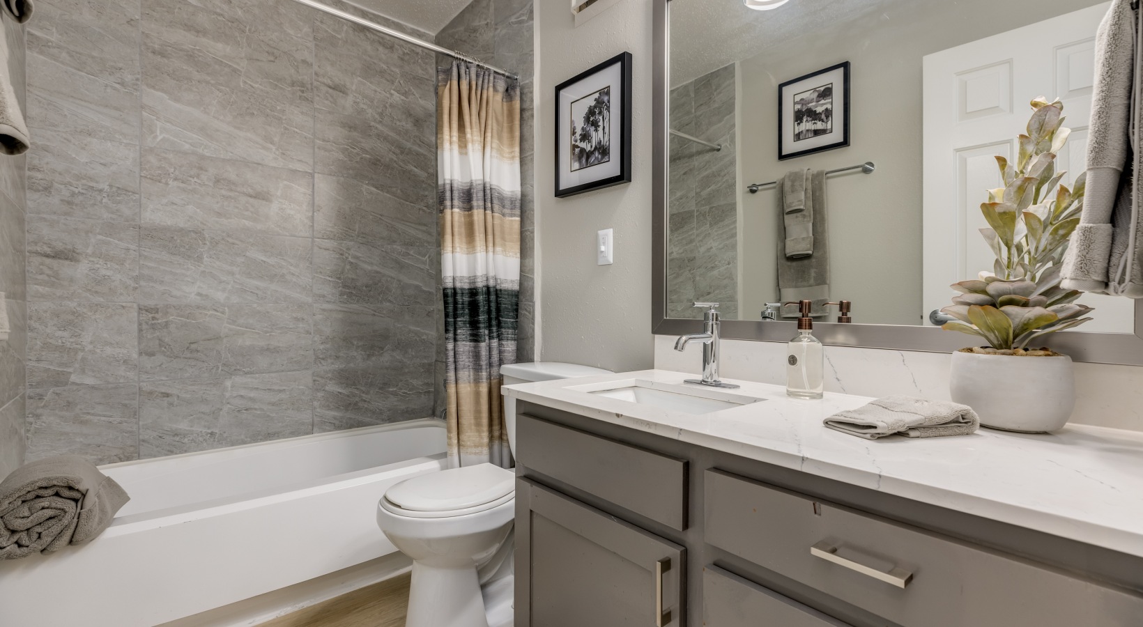 a bathroom with gray cabinets and a white sink at The Landon