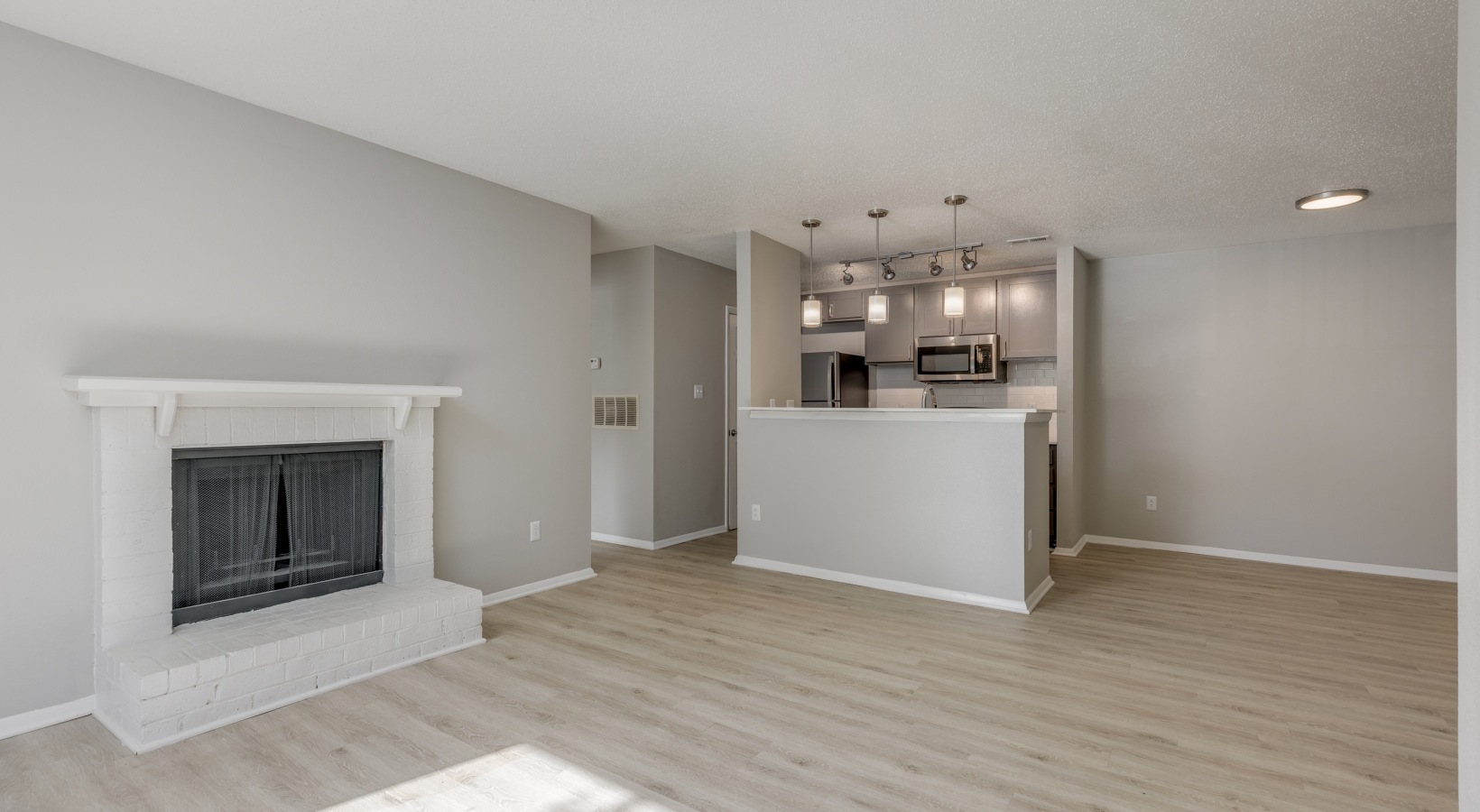 an empty living room with a fireplace and hardwood floors at The Landon